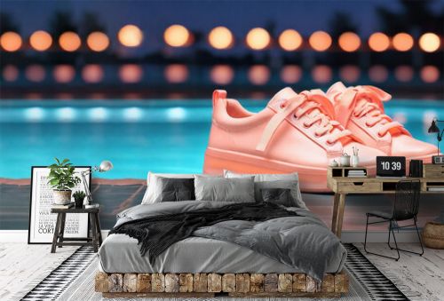 Peach-colored sneakers stand on the background of an outdoor pool