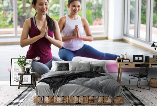 Two Asian women praticing and training yoga together at home with basic muscular stretching and body balance.