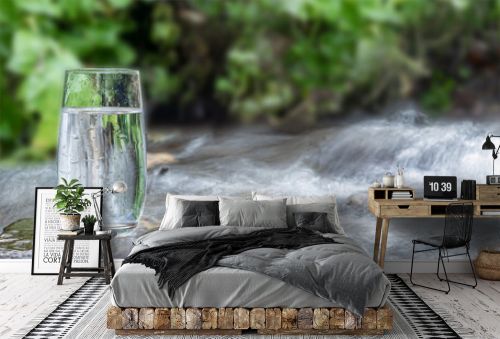 a glass of clean transparent drinking water in a transparent glass on a stone in a green forest near a stream or mountain spring. healthy food and diet, beautiful background copy space