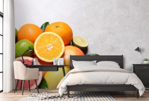 Pile of different fresh citrus fruits and leaves on grey textured table, flat lay. Space for text