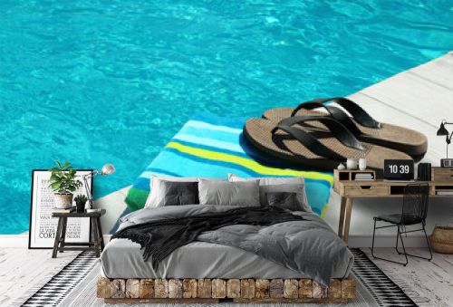 Beach accessories on wooden deck near swimming pool. Space for text
