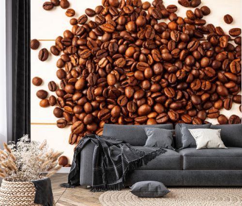 Coffee beans scattered on a light wooden background. The concept of growing and making coffee. Top view, minimalism.