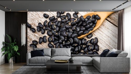 Black beans ( black gram, vigna mungo ) in wooden scoop isolated on wood table background. 