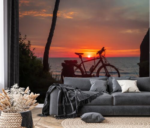 Peaceful scene with a bike silhouette against a colorful ocean sunset. Concept of leisure and travel.