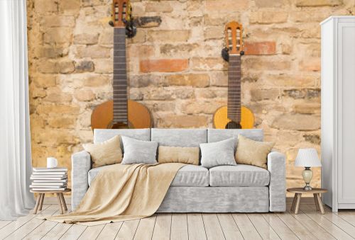 Two acoustic guitars hanging on brick wall background indoors. V
