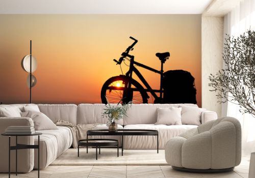 Silhouette of a bicycle against the orange sky at sunrise
