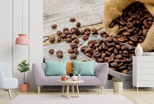 Dark roasted coffee beans with scoop on wooden background
