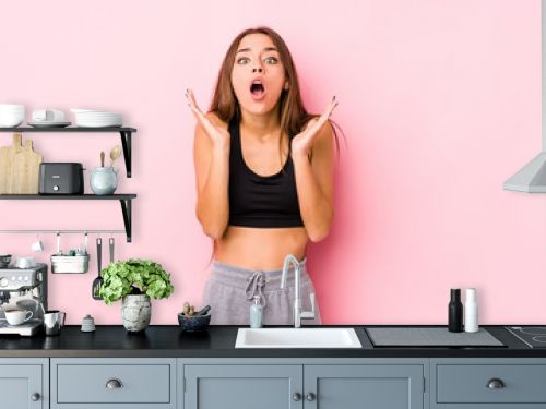 Young caucasian fitness woman posing in a pink background surprised and shocked.